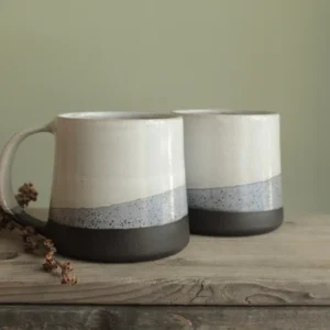 Modern minimalist porcelain mugs with three-tone design on rustic wood.